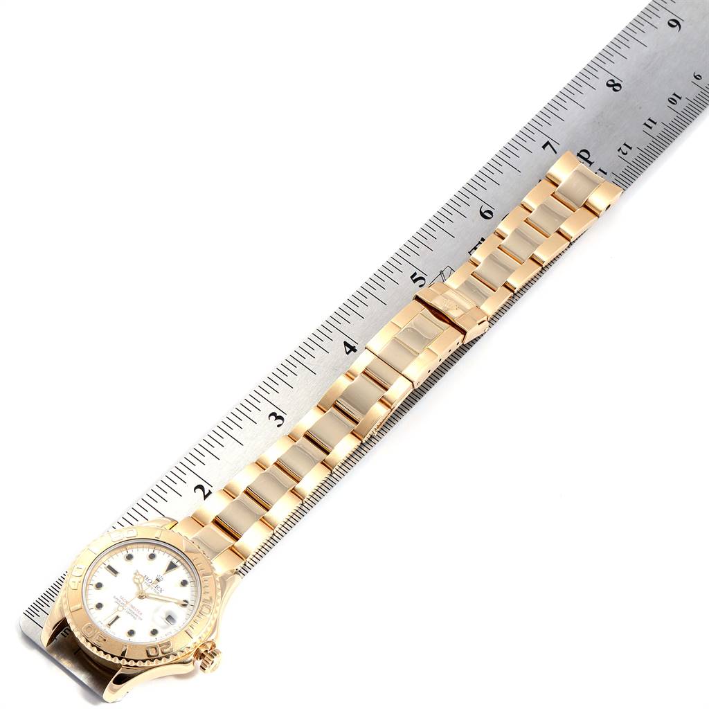 This image shows a Rolex Yacht-Master 68628 Yellow Gold White Dial 68628 Yellow Gold White Dial watch laid flat next to a ruler, highlighting the watch face and bracelet.