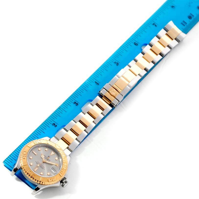 The Rolex Yacht-Master 68623 Men's Stainless Steel Grey Dial 68623 Men's Stainless Steel Grey Dial watch is shown lying flat next to a blue ruler, displaying the face, bezel, and bracelet.