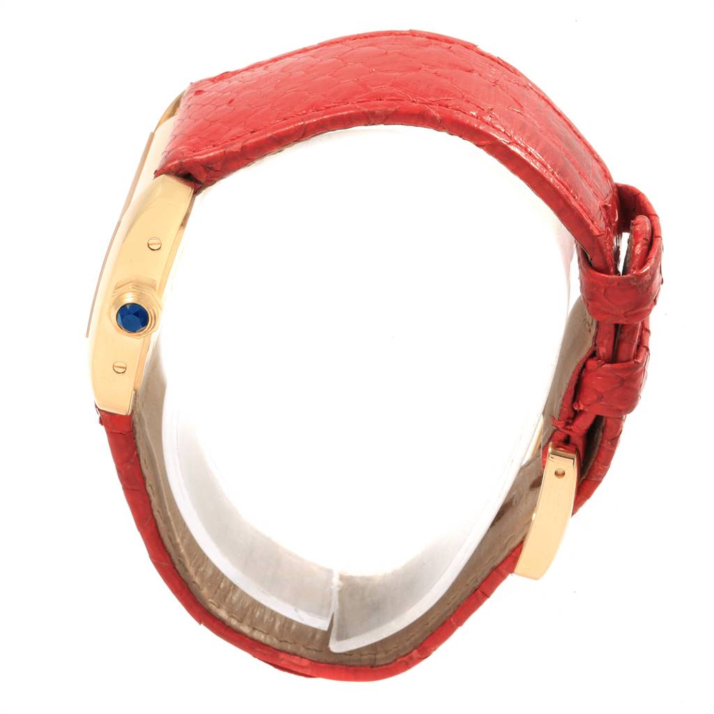 The Cartier Tank Divan W6300356 Women's Yellow Gold Silver Dial W6300356 Women's Yellow Gold Silver Dial watch is shown from the side, highlighting its gold case, blue crown jewel, and red leather strap.