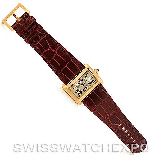 The Cartier Tank Divan W6300356 Women's Yellow Gold White Dial W6300356 Women's Yellow Gold White Dial watch is shown from a top-down angle, displaying its face, red strap, and gold buckle.