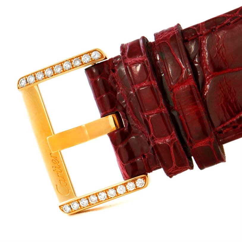 The image shows a close-up of the buckle of a Cartier Tank Divan WA301170? Men's Yellow Gold Silver Dial WA301170? Men's Yellow Gold Silver Dial watch, featuring a gold clasp with embedded diamonds and a red leather strap.