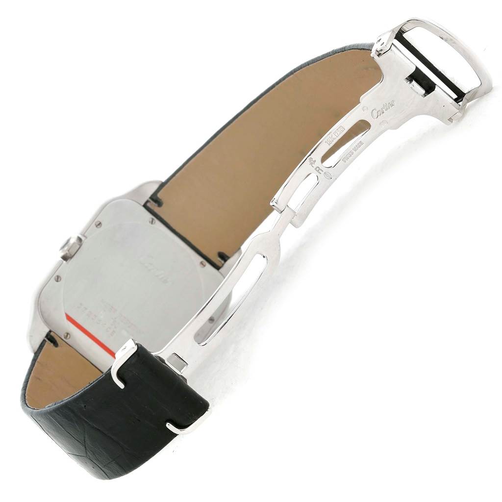 The image shows the open clasp and back of the Santos Dumont watch by Cartier, revealing part of the leather strap and metal clasp.
