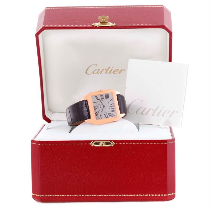 The Cartier Santos Dumont W2006951 Men
s Rose Gold Silver Dial W2006951 Men
s Rose Gold Silver Dial watch is displayed front-on in an open red box with a white booklet beside it.