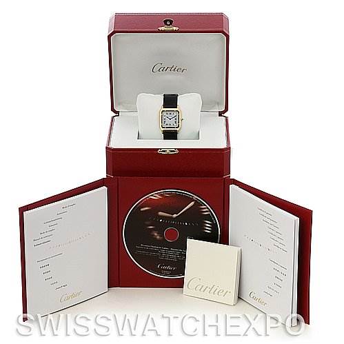 This image shows a Cartier Santos Dumont Yellow Gold White Dial Yellow Gold White Dial watch with its box, manuals, and a CD from a front angle.