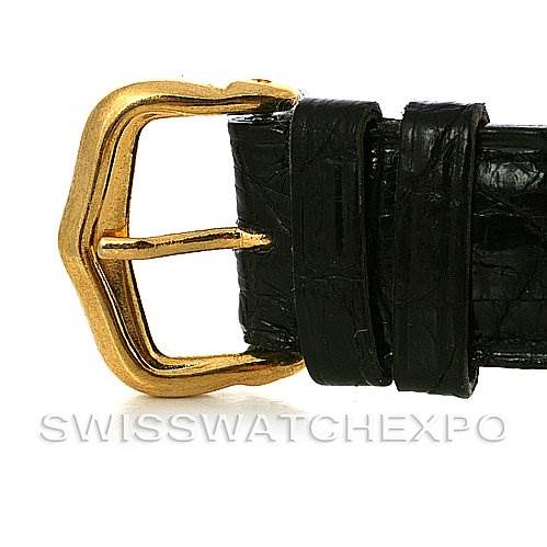 This image shows a close-up of the gold buckle and black leather strap of a Santos Dumont model by Cartier.