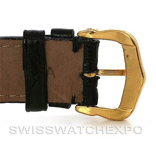 This image shows a close-up of the gold buckle and leather strap of a Santos Dumont watch by Cartier.