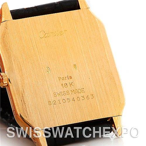 The image shows the back case of a Cartier Santos Dumont Men's Yellow Gold White Dial Men's Yellow Gold White Dial watch, highlighting the engravings and the 18K gold material.