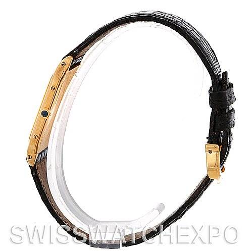 The image shows a side view of the Cartier Santos Dumont Men's Yellow Gold White Dial Men's Yellow Gold White Dial watch, highlighting its thin case, leather strap, and deployment clasp.