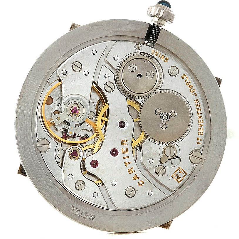 The image shows the internal mechanism of a Santos Dumont watch by Cartier, highlighting gears, springs, and the jewelled movement.