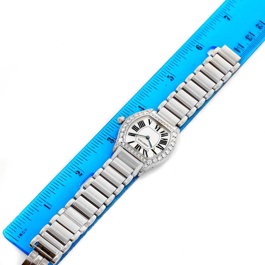 The Cartier Tortue WA5072W9 Women's White Gold Silver Dial WA5072W9 Women's White Gold Silver Dial watch is shown flat against a blue ruler, displaying its face, bracelet, and bezel.