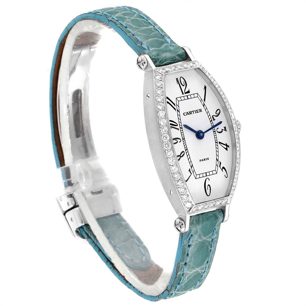The Cartier Tortue WE400131 Women's White Gold White Dial WE400131 Women's White Gold White Dial watch is shown at a three-quarter view displaying its face, bezel with diamond accents, and green leather strap.