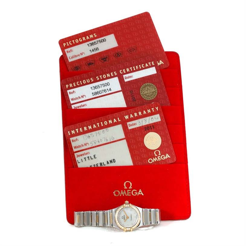 The image shows the Omega 1365.75.00 Women
s Steel and Gold (two tone) Mother of Pearl Dial 1365.75.00 Women
s Steel and Gold (two tone) Mother of Pearl Dial Constellation Mini Steel Yellow Gold Diamond Watch 1365.75.00 with its warranty cards and certificates.