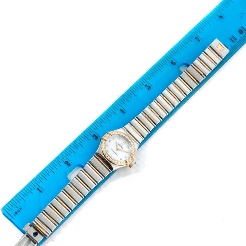 The Omega 1365.75.00 Women
s Steel and Gold (two tone) Mother of Pearl Dial 1365.75.00 Women
s Steel and Gold (two tone) Mother of Pearl Dial Constellation Mini Steel Yellow Gold Diamond Watch 1365.75.00 is displayed flat from above with a ruler for scale, showing the dial, bezel, and bracelet.