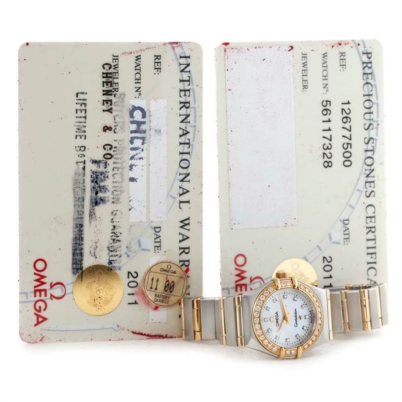 The image shows the Omega 1267.75.00 Women
s Steel and Gold (two tone) Mother of Pearl Dial 1267.75.00 Women
s Steel and Gold (two tone) Mother of Pearl Dial Constellation My Choice Mini Diamond Watch 1267.75.00 along with its international warranty and certification cards.