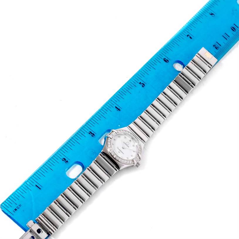 The Omega 1465.71.00 Women
s Stainless Steel Mother of Pearl Dial 1465.71.00 Women
s Stainless Steel Mother of Pearl Dial Constellation My Choice Ladies Mini Diamond Watch 1465.71.00 is shown from the top view with its entire band and watch face next to a ruler.