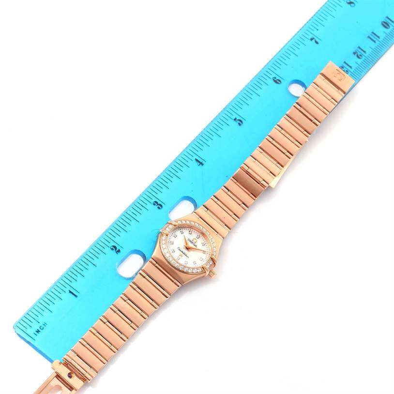 This image features the Omega 1167.75.00 Women's Rose Gold Mother of Pearl Dial 1167.75.00 Women's Rose Gold Mother of Pearl Dial Constellation 95 18K Rose Gold Diamond Watch 1167.75.00 fully extended with a ruler for size reference.
