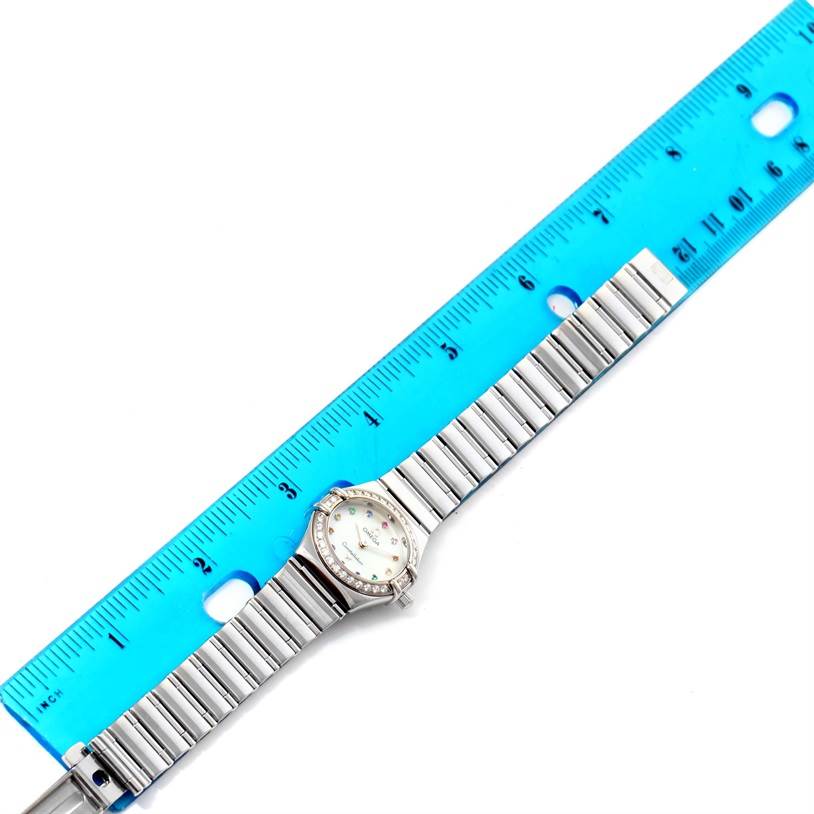 The Omega 1465.79.00 Women
s Stainless Steel Mother of Pearl Dial 1465.79.00 Women
s Stainless Steel Mother of Pearl Dial Constellation Iris My Choice Steel Multi Stone Watch 1465.79.00 is shown from a top-down angle next to a blue ruler, displaying the watch
s band and face.