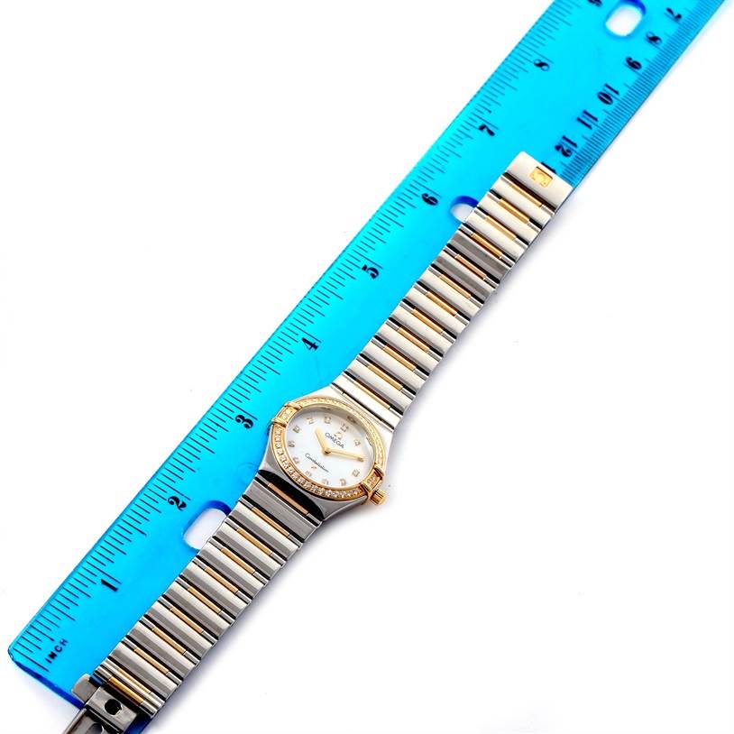 The Omega 1376.75.00 Women
s Steel and Gold (two tone) Mother of Pearl Dial 1376.75.00 Women
s Steel and Gold (two tone) Mother of Pearl Dial Constellation My Choice 1376.75.00 watch is shown from a top-down angle along with a blue ruler for measurement.
