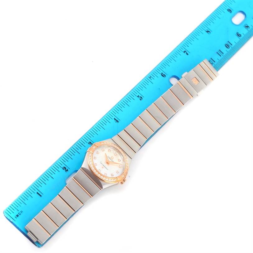 The Omega 123.25.27.60.55.009 Women
s Steel and Gold (two tone) Mother of Pearl Dial 123.25.27.60.55.009 Women
s Steel and Gold (two tone) Mother of Pearl Dial Constellation Diamond Steel Rose Gold Watch 123.25.27.60.55.009 is shown flat with the entire face and band visible, next to a blue ruler for scale.
