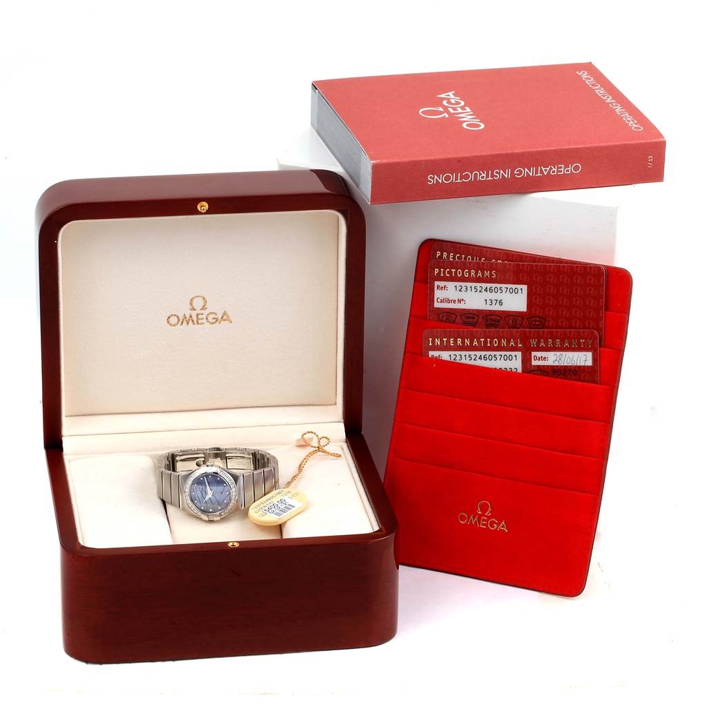 The Omega 123.15.24.60.57.001 Women's Stainless Steel Mother of Pearl Dial 123.15.24.60.57.001 Women's Stainless Steel Mother of Pearl Dial Constellation Quartz 24 MOP Diamond Watch 123.15.24.60.57.001 is shown in its box with accompanying documents and tags.