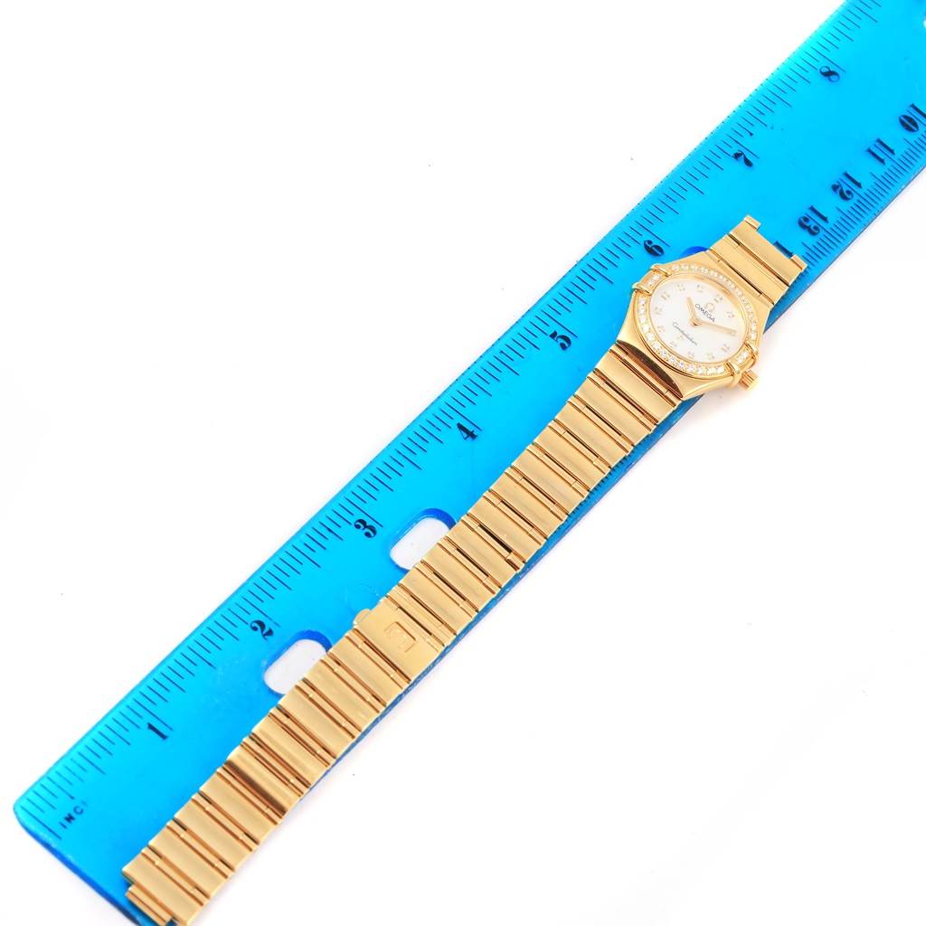 The Omega 1164.75.00 Women's Yellow Gold Mother of Pearl Dial 1164.75.00 Women's Yellow Gold Mother of Pearl Dial Constellation My Choice Yellow Gold MOP Diamond Ladies Watch model 1164.75.00 is shown from an overhead angle next to a blue ruler.