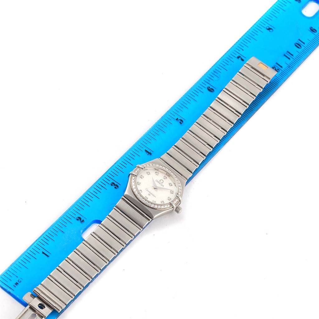 The Omega 1460.75.00 Women's Stainless Steel Mother of Pearl Dial 1460.75.00 Women's Stainless Steel Mother of Pearl Dial Constellation 95 Mini MOP Diamonds Ladies Watch 1460.75.00 is shown flat with its bracelet extended next to a ruler.