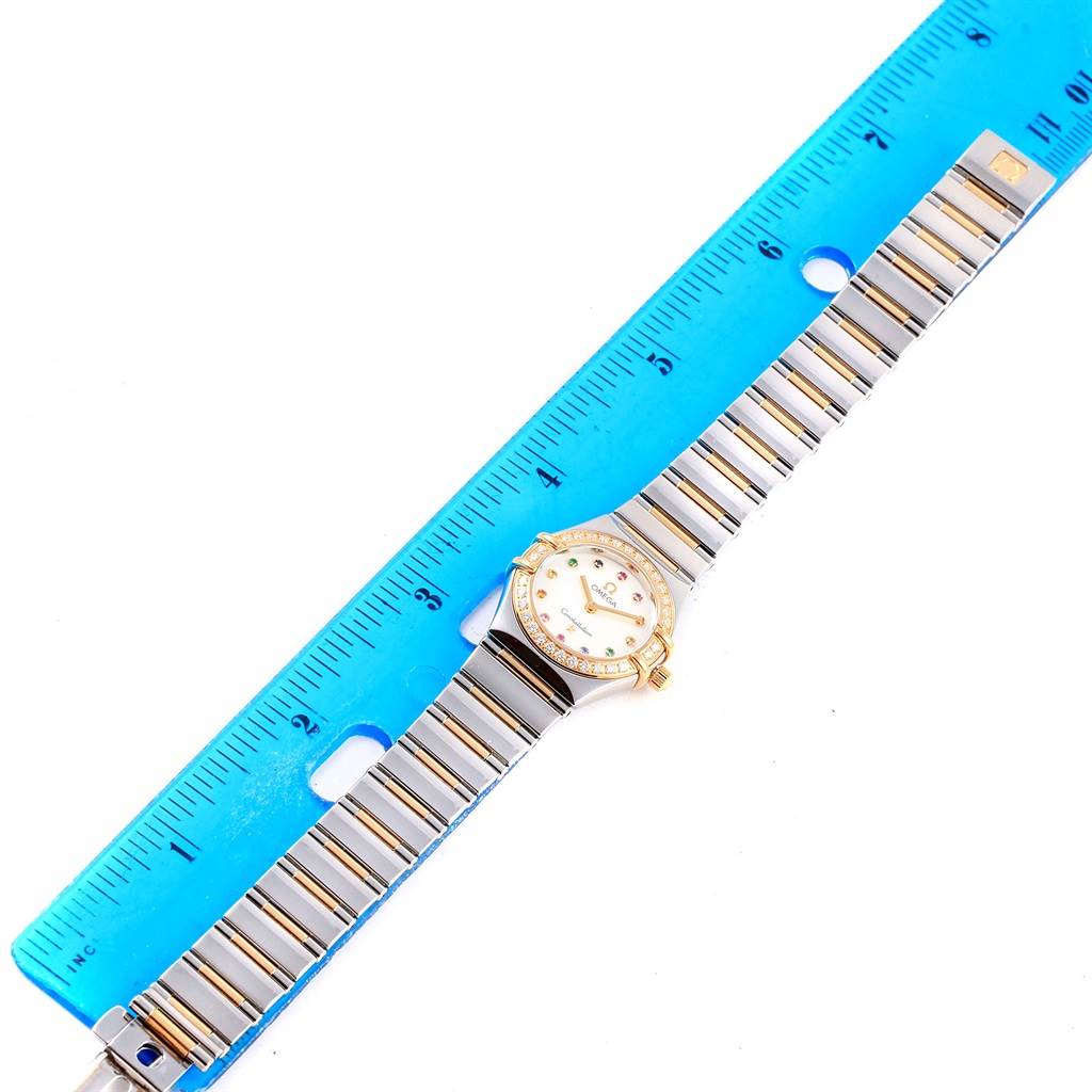 The Omega 1365.79.00 Women
s Steel and Gold (two tone) Mother of Pearl Dial 1365.79.00 Women
s Steel and Gold (two tone) Mother of Pearl Dial Constellation Iris Steel Yellow Gold Multi Stone Watch 1365.79.00 is shown from a top-down angle alongside a ruler for scale.