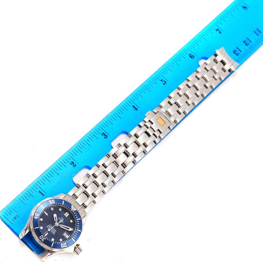 This image shows the Omega Women's Stainless Steel Blue Dial Women's Stainless Steel Blue Dial Seamaster Professional 300M Blue Wave Dial 28mm Ladies Watch laid flat alongside a blue ruler.