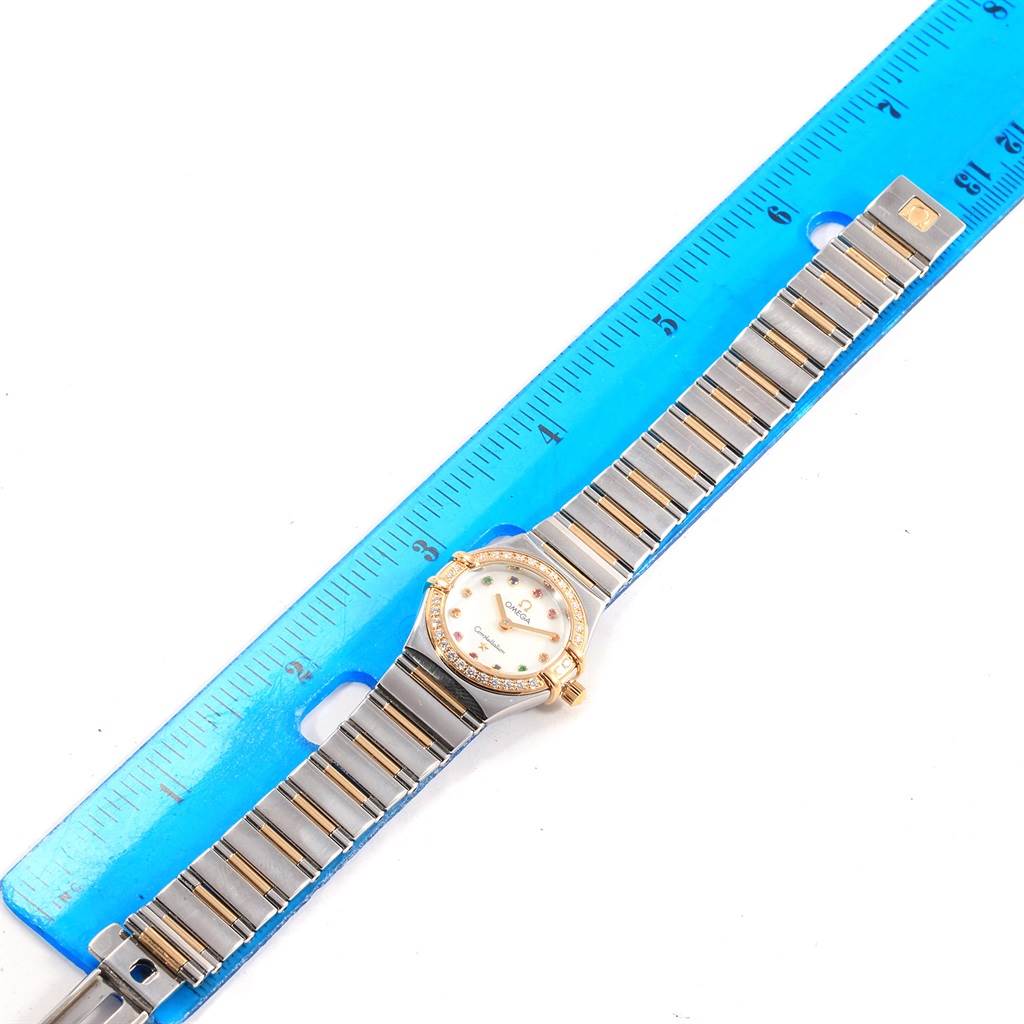 The Omega 1365.79.00 Women
s Steel and Gold (two tone) Mother of Pearl Dial 1365.79.00 Women
s Steel and Gold (two tone) Mother of Pearl Dial Constellation Iris 1365.79.00 watch is shown from a top-down angle, placed next to a blue ruler for scale.