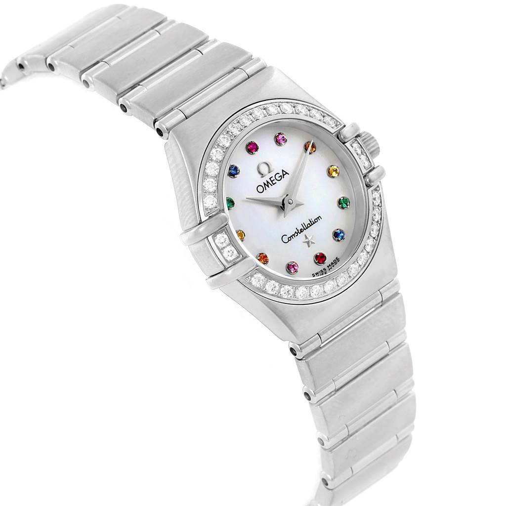 The image shows a Constellation Iris Rainbow Multi Stone Watch 1476.79.00 by Omega 1476.79.00 Women's Stainless Steel Mother of Pearl Dial 1476.79.00 Women's Stainless Steel Mother of Pearl Dial, featuring a colorful gem-set dial and metal bracelet at a tilted angle.
