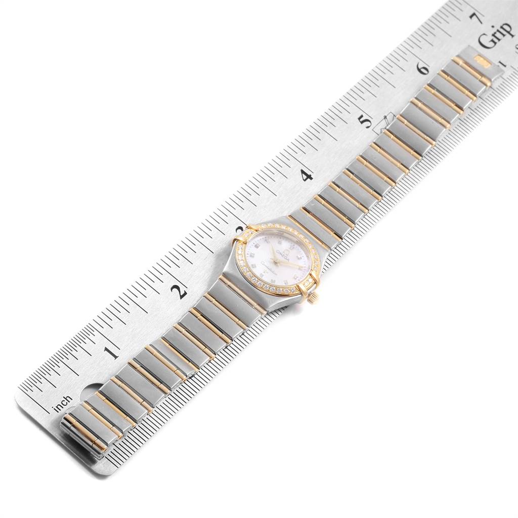 The image shows the Omega 1267.75.00 Women's Steel and Gold (two tone) Mother of Pearl Dial 1267.75.00 Women's Steel and Gold (two tone) Mother of Pearl Dial Constellation Mini Mother of Pearl Diamond Watch 1267.75.00 from a top-down angle beside a ruler.