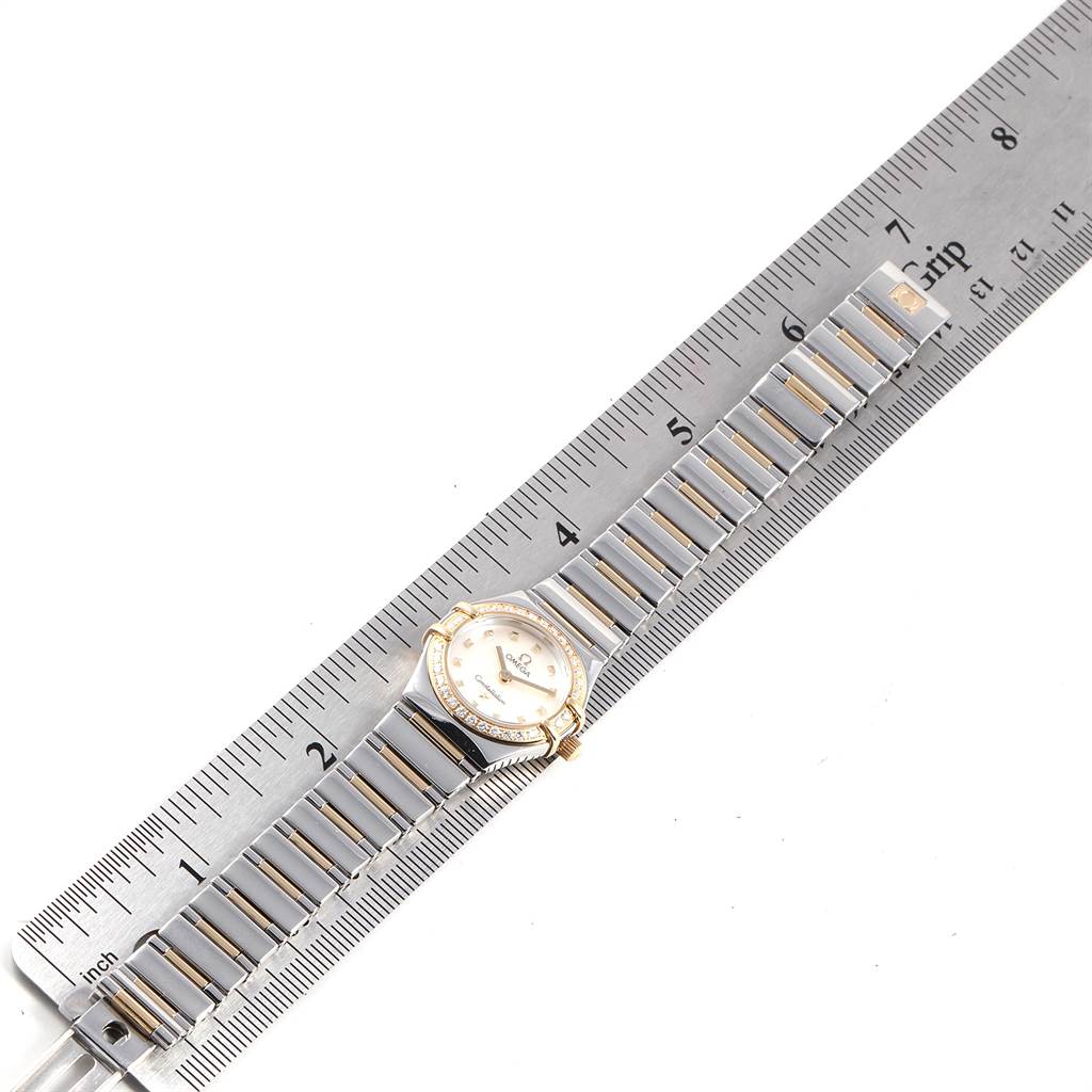 The Omega 1365.71.00 Women's Steel and Gold (two tone) Mother of Pearl Dial 1365.71.00 Women's Steel and Gold (two tone) Mother of Pearl Dial Ladies Constellation Steel Yellow Gold Diamond Mini 1365.71.00 watch is shown from a top view, aligned with a ruler.