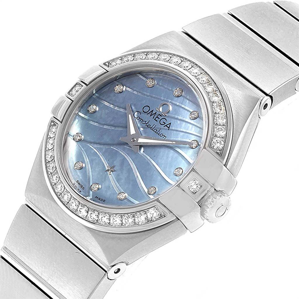 The image shows a close-up, angled view of the Omega 123.15.24.60.57.001 Women's Stainless Steel Mother of Pearl Dial 123.15.24.60.57.001 Women's Stainless Steel Mother of Pearl Dial Constellation Quartz 24 MOP Diamond Watch 123.15.24.60.57.001, focusing on its diamond-studded bezel and blue textured dial.