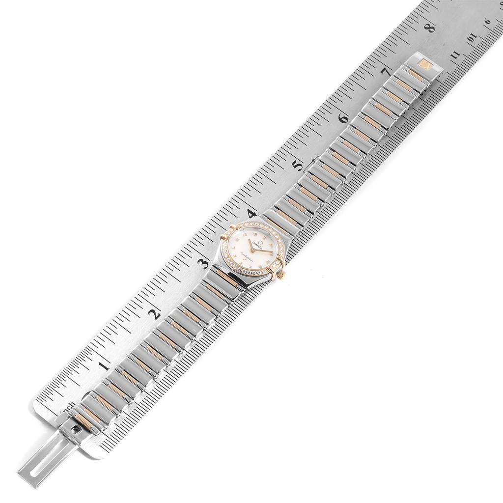 The Omega 1365.71.00 Women's Steel and Gold (two tone) Mother of Pearl Dial 1365.71.00 Women's Steel and Gold (two tone) Mother of Pearl Dial Constellation Steel Yellow Gold Diamond Ladies Watch 1365.71.00 is shown from a top-down angle, with the strap and face aligned alongside a ruler.