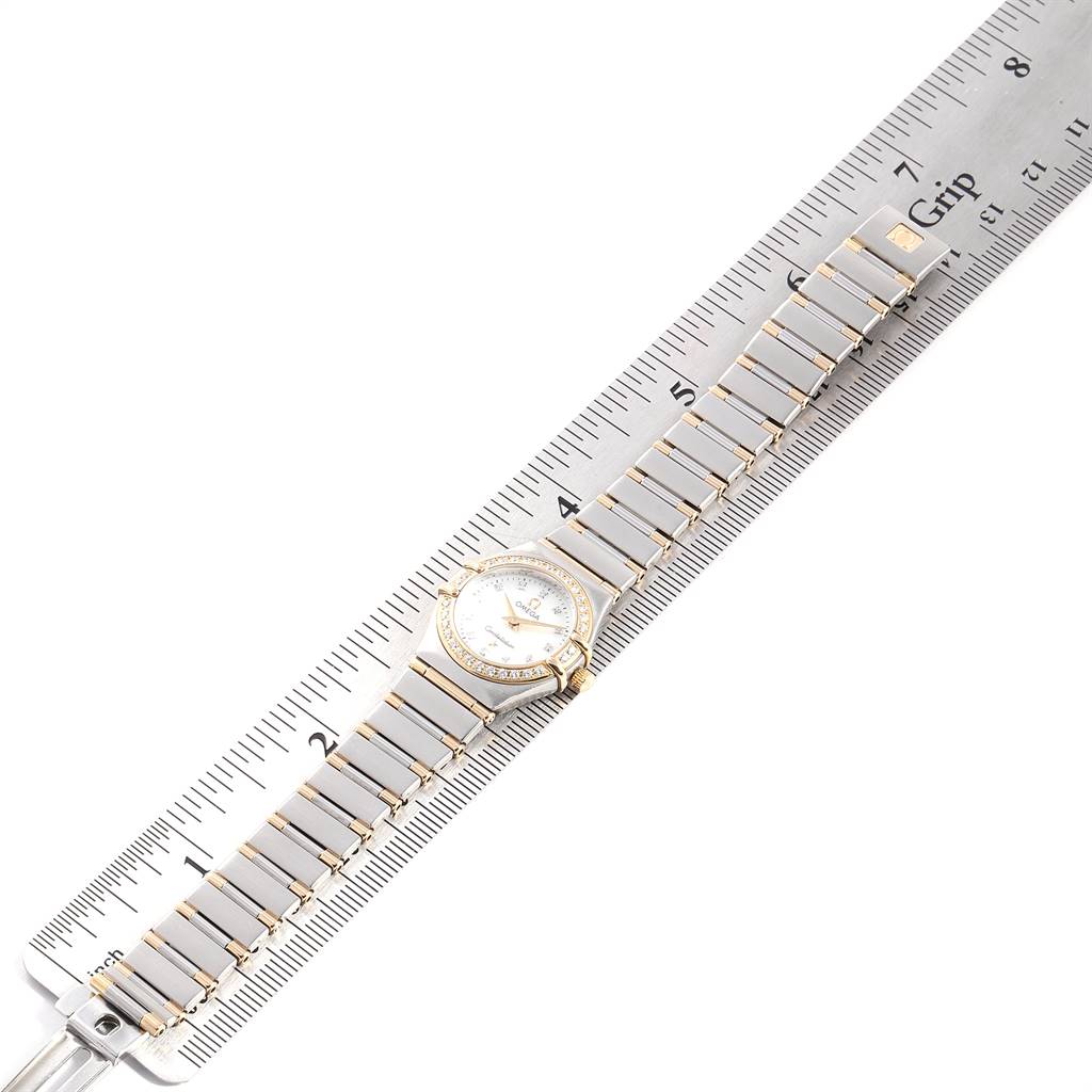 The Omega 1267.75.00 Women's Steel and Gold (two tone) Mother of Pearl Dial 1267.75.00 Women's Steel and Gold (two tone) Mother of Pearl Dial Constellation MOP Diamond Ladies Watch 1267.75.00 is shown lying flat next to a ruler, displaying the full band and face.