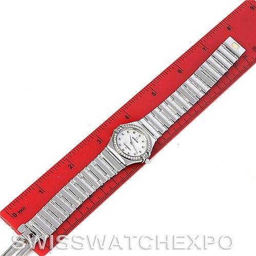The image shows an Omega 1475.71.00 Women
s Stainless Steel Mother of Pearl Dial 1475.71.00 Women
s Stainless Steel Mother of Pearl Dial Constellation My Choice Ladies Quartz Small Watch 1475.71.00 lying flat next to a red ruler.