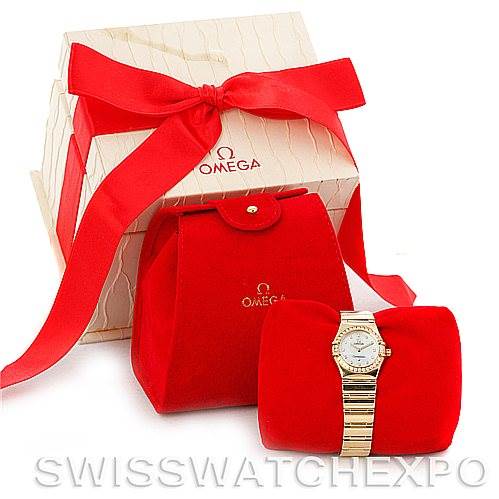 The Omega 1164.75.00 Women's Yellow Gold Mother of Pearl Dial 1164.75.00 Women's Yellow Gold Mother of Pearl Dial Constellation 18K Yellow Gold Diamond Mini 1164.75.00 Watch is shown alongside its packaging and a red pouch.