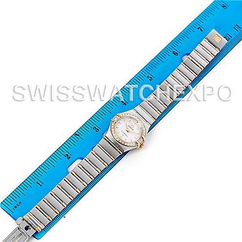 The image shows an overhead view of an Omega Women's Steel and Gold (two tone) White Dial Women's Steel and Gold (two tone) White Dial Constellation Mini Steel and Gold Diamond Watch placed alongside a blue ruler.