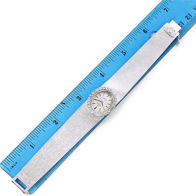 The image shows an Omega Women's White Gold Silver Dial Women's White Gold Silver Dial Deville Vintage Ladies 18k White Gold Diamond Watch laid flat against a blue ruler for measurement.