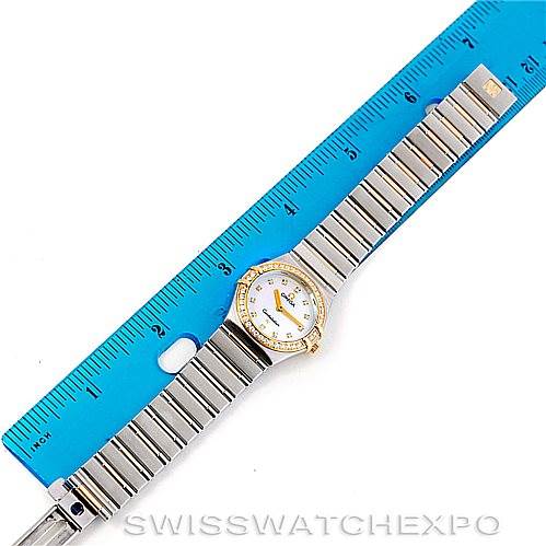 The image shows the Omega 1376.75.00 Women
s Steel and Gold (two tone) Mother of Pearl Dial 1376.75.00 Women
s Steel and Gold (two tone) Mother of Pearl Dial Constellation My Choice Steel and Gold Diamond Watch 1376.75.00 from a top-down angle, with its band stretched out next to a ruler.