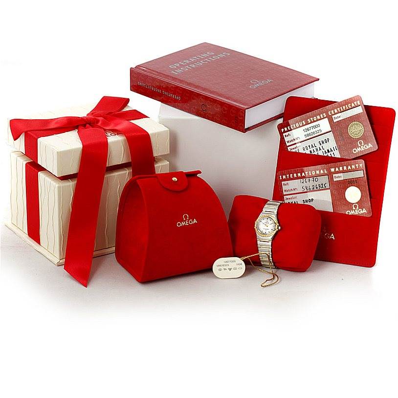 The image displays an Omega 1267.70.00 Women
s Steel and Gold (two tone) Mother of Pearl Dial 1267.70.00 Women
s Steel and Gold (two tone) Mother of Pearl Dial Constellation Ladies Diamond Mini Watch 1267.70.00 with gift packaging, warranty cards, and a manual.