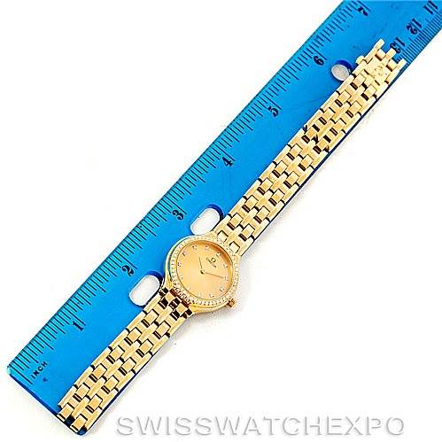 The DeVille Ladies 18K Yellow Gold Diamond Watch by Omega Women's Yellow Gold Champagne Dial Women's Yellow Gold Champagne Dial is shown lying flat next to a blue ruler for scale.