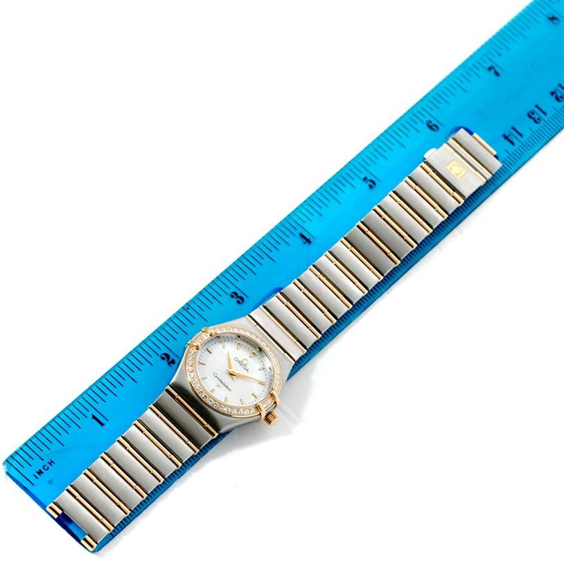 The Omega 1277.70.00 Women
s Steel and Gold (two tone) Mother of Pearl Dial 1277.70.00 Women
s Steel and Gold (two tone) Mother of Pearl Dial Constellation My Choice Steel Gold Diamond Watch 1277.70.00 is shown from a top-down angle, alongside a ruler.
