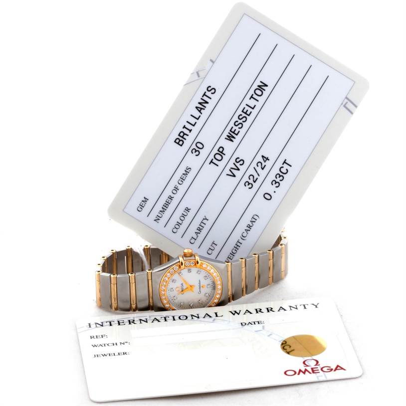 The Omega 1267.75.00 Women
s Steel and Gold (two tone) Mother of Pearl Dial 1267.75.00 Women
s Steel and Gold (two tone) Mother of Pearl Dial Constellation My Choice Steel Gold Diamond Watch 1267.75.00 is shown laying flat with its warranty and gem certification cards visible.