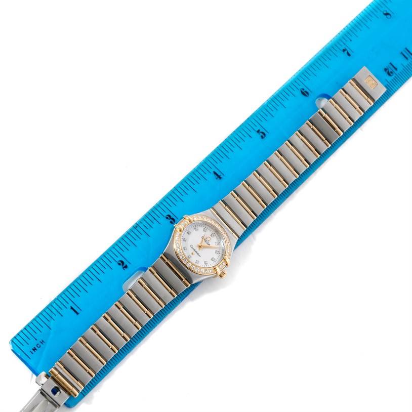 The image shows the Omega 1267.75.00 Women
s Steel and Gold (two tone) Mother of Pearl Dial 1267.75.00 Women
s Steel and Gold (two tone) Mother of Pearl Dial Constellation My Choice Steel Gold Diamond Watch 1267.75.00 laid flat next to a blue ruler, displaying the watch face and bracelet.
