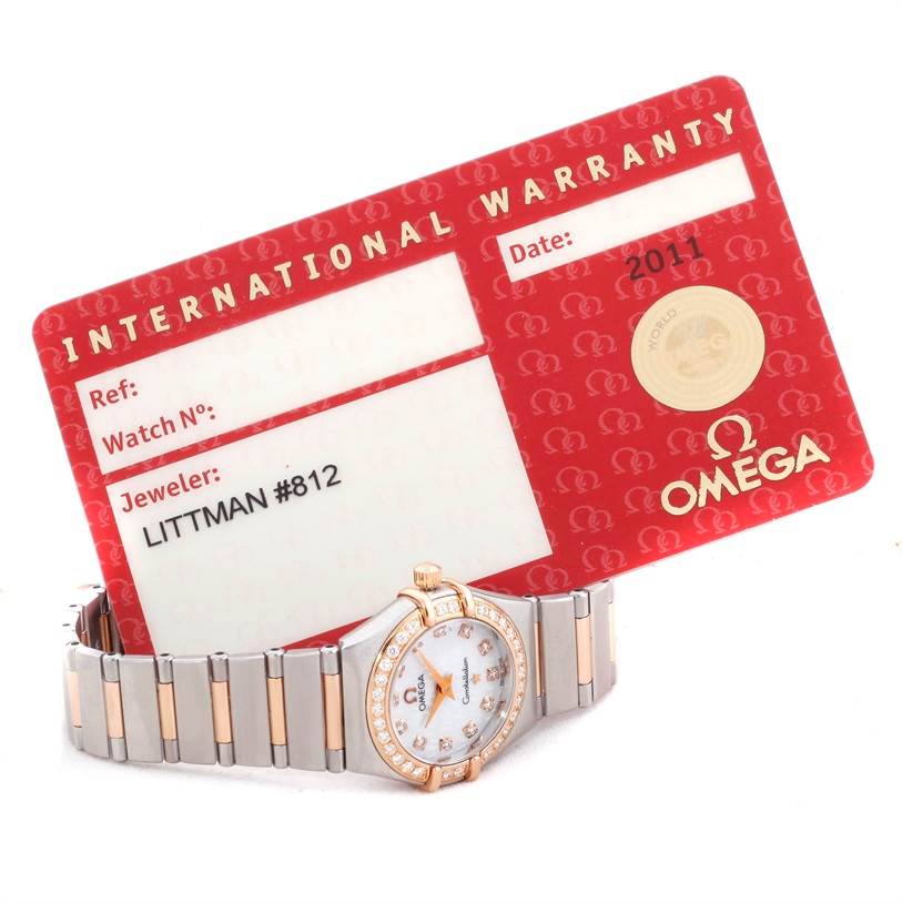 The image shows the Omega 1360.75.00 Women
s Steel and Gold (two tone) Mother of Pearl Dial 1360.75.00 Women
s Steel and Gold (two tone) Mother of Pearl Dial Constellation My Choice Mini Diamond Watch 1360.75.00 with its International Warranty card.