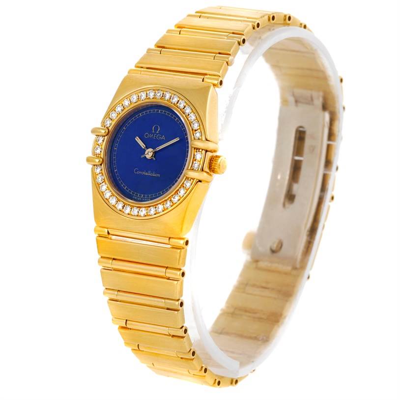 The image shows an Omega Women
s Blue Dial Women
s Blue Dial Constellation 18K Yellow Gold Diamond Lapis Dial Watch from a three-quarter angle, showcasing the dial, bezel, and bracelet.