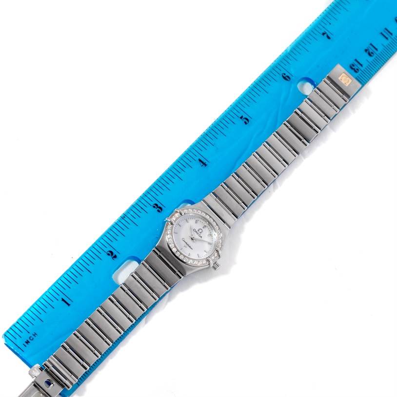 The image shows an overhead view of the Omega 1466.71.00 Women
s Stainless Steel Mother of Pearl Dial 1466.71.00 Women
s Stainless Steel Mother of Pearl Dial Constellation 95 My Choice Ladies Mini Watch 1466.71.00 model next to a blue ruler.