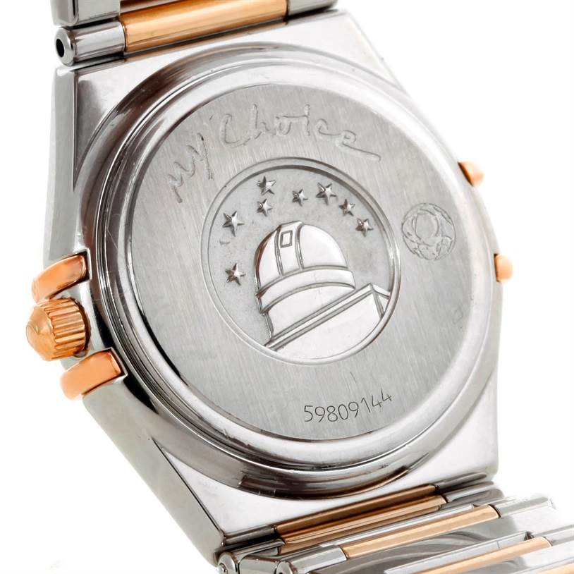 The image shows the case back and part of the bracelet of the Omega 1358.79.00 Women
s Steel and Gold (two tone) Mother of Pearl Dial 1358.79.00 Women
s Steel and Gold (two tone) Mother of Pearl Dial Constellation Iris Steel Rose Gold Multi Stone Watch 1358.79.00 model.