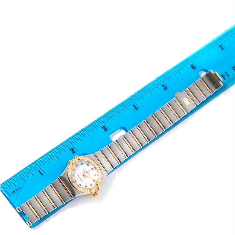 The Omega 1367.79.00 Women
s Steel and Gold (two tone) Mother of Pearl Dial 1367.79.00 Women
s Steel and Gold (two tone) Mother of Pearl Dial Constellation Iris Steel Yellow Gold Multi Stone Watch 1367.79.00 is shown laid flat beside a blue ruler.